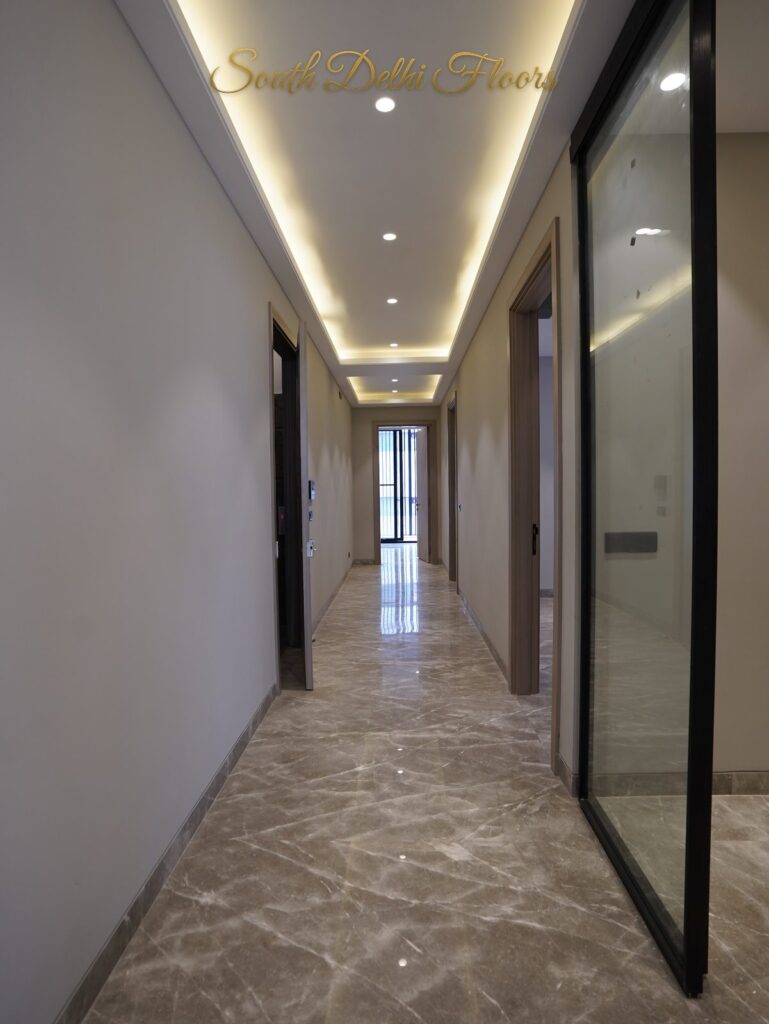 Corridor with a glass sliding partition, cove lighting and marble flooring at an RPB Homes JCR Homes luxury property in South Delhi by Mahavir Bihani and Rajat Bihani