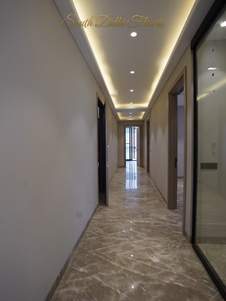 End view of the cove-lit passage with marble floor and glass partition at an RPB Homes JCR Homes luxury residence in South Delhi by developers Mahavir Bihani and Rajat Bihani