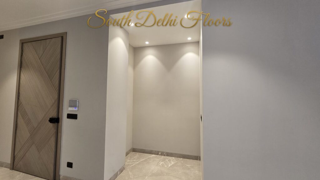 Foyer with a chevron wooden door and cream marble floor at an RPB Homes JCR Homes luxury home in South Delhi by builders Mahavir Bihani and Rajat Bihani