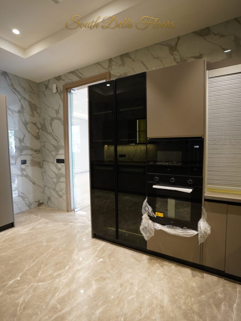 Kitchen with a built-in oven tower and tall black glass units at an RPB Homes JCR Homes luxury home in South Delhi by builders Mahavir Bihani and Rajat Bihani