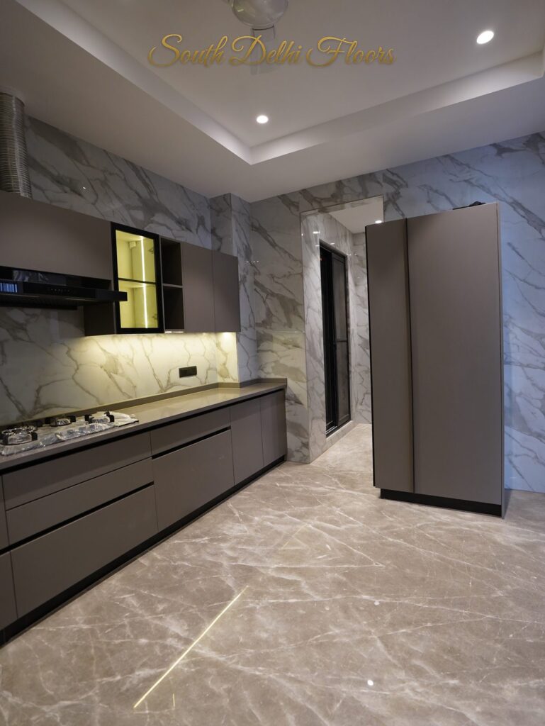 Kitchen with tall storage units, grey cabinets and marble-clad walls at an RPB Homes JCR Homes luxury builder floor in South Delhi by Mahavir Bihani and Rajat Bihani