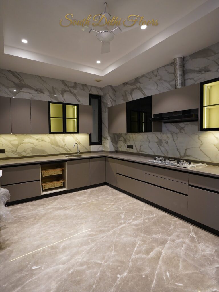 L-shaped modular kitchen with a white marble splashback and backlit glass cabinets at an RPB Homes JCR Homes luxury home in South Delhi by builders Mahavir Bihani and Rajat Bihani