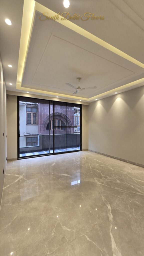 Living hall with a layered cove ceiling and glass balcony wall at an RPB Homes JCR Homes luxury property in South Delhi by Mahavir Bihani and Rajat Bihani