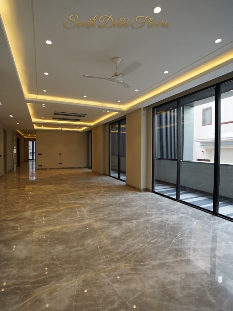 Side view of the living room with cove ceiling and balcony glass wall at an RPB Homes JCR Homes luxury builder floor in South Delhi by Mahavir Bihani and Rajat Bihani