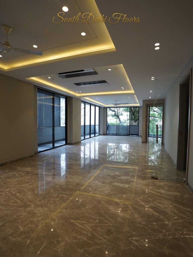 Spacious living room with a cove-lit false ceiling, floor-to-ceiling glass and polished marble flooring at an RPB Homes JCR Homes luxury builder floor in South Delhi by Mahavir Bihani and Rajat Bihani