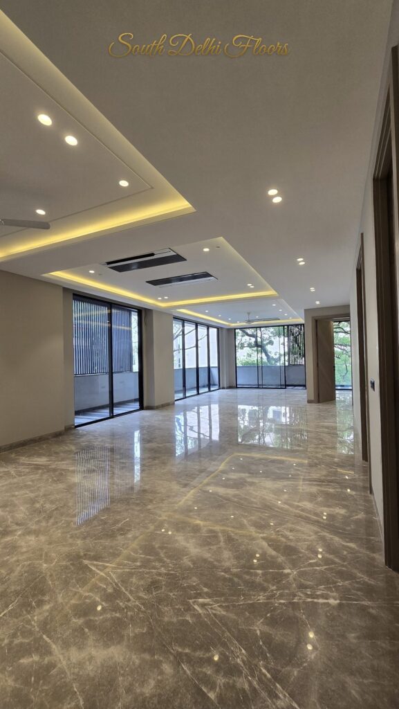 Living room with a layered cove ceiling and glass balcony wall at an RPB Homes JCR Homes luxury home in South Delhi by builders Mahavir Bihani and Rajat Bihani