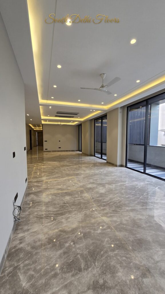 Long living room with a cove-lit ceiling and glass sliding wall to the balcony at an RPB Homes JCR Homes luxury builder floor in South Delhi by Mahavir Bihani and Rajat Bihani