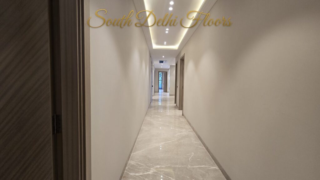 Long corridor with cove lighting and cream marble floor at an RPB Homes JCR Homes luxury home in South Delhi by builders Mahavir Bihani and Rajat Bihani