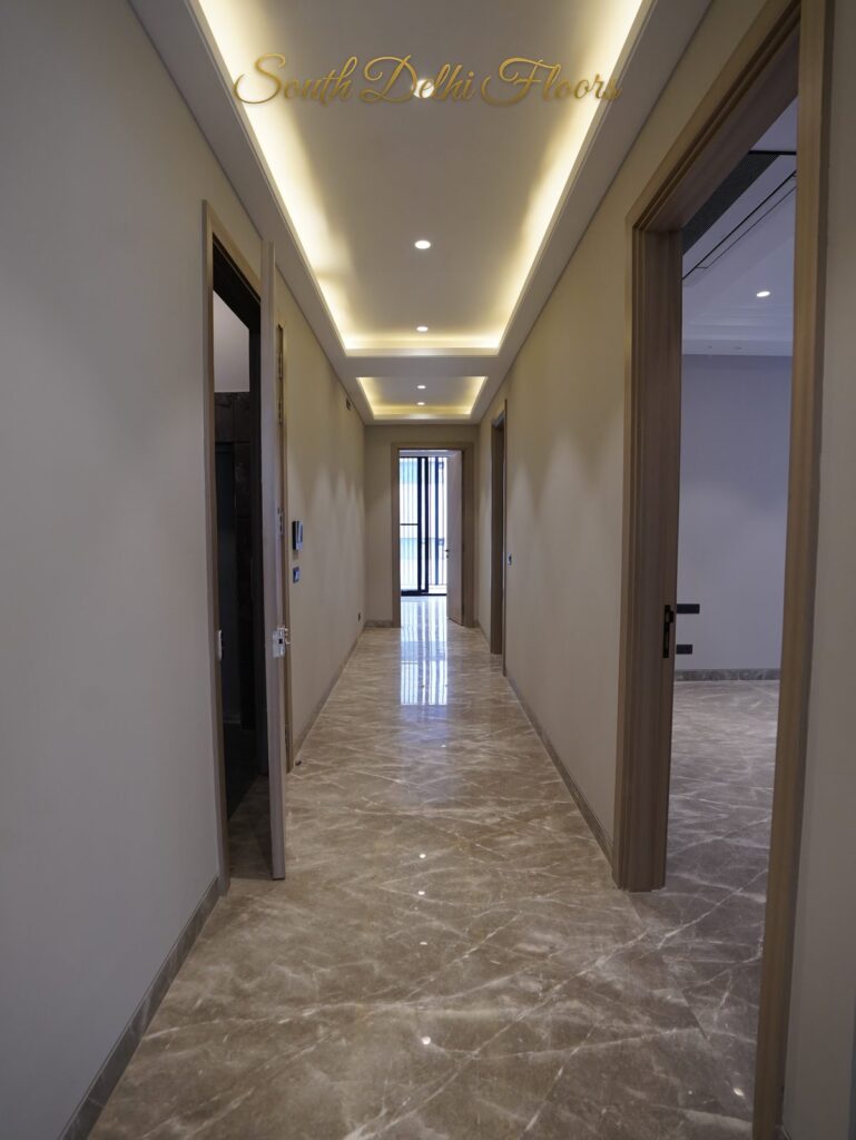 Marble passage with cove lighting and wooden doors opening to the rooms at an RPB Homes JCR Homes luxury residence in South Delhi by developers Mahavir Bihani and Rajat Bihani