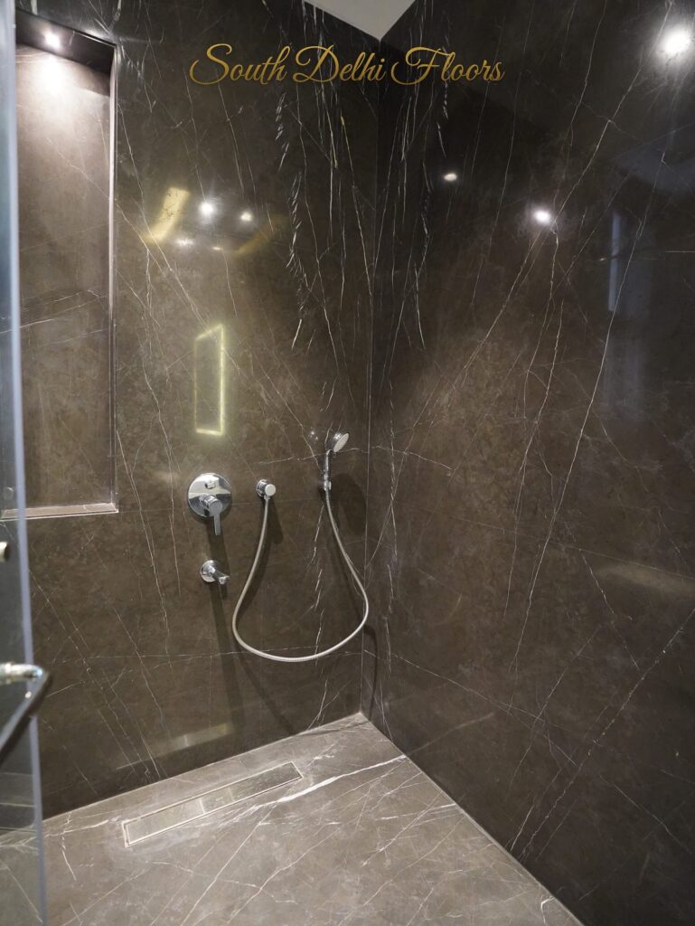 Shower enclosure with dark marble, a rain shower and lit niche at an RPB Homes JCR Homes luxury builder floor in South Delhi by Mahavir Bihani and Rajat Bihani