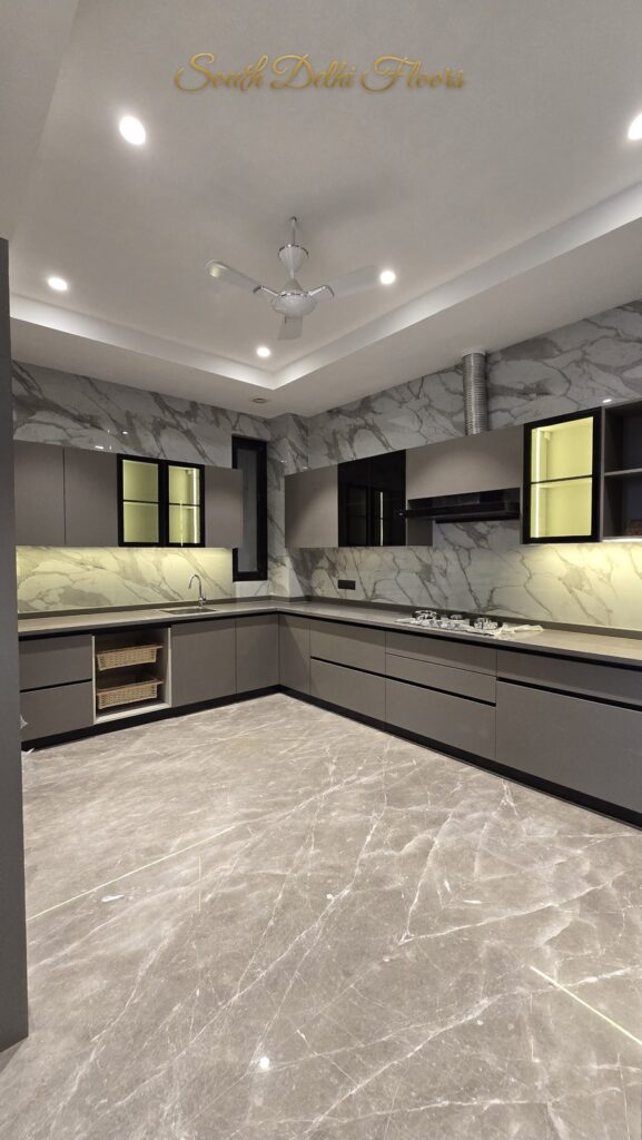 Wide-angle view of the U-shaped kitchen with marble walls and grey cabinets at an RPB Homes JCR Homes luxury residence in South Delhi by developers Mahavir Bihani and Rajat Bihani