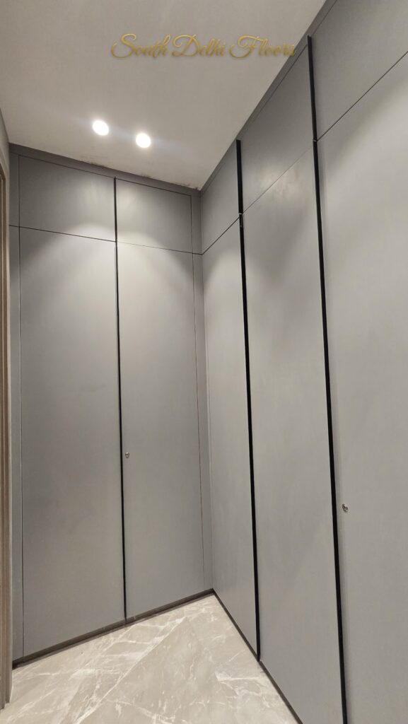 Walk-in wardrobe with light grey panelled doors and marble floor at an RPB Homes JCR Homes luxury home in South Delhi by builders Mahavir Bihani and Rajat Bihani