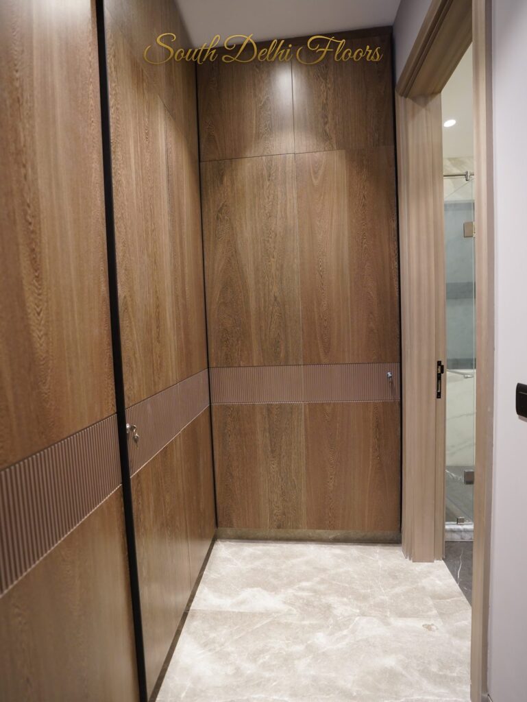 Walk-in wardrobe with wood panelled doors leading to the bathroom at an RPB Homes JCR Homes luxury home in South Delhi by builders Mahavir Bihani and Rajat Bihani